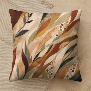 May include: A square throw pillow featuring an abstract botanical pattern with elongated leaf shapes in shades of rust, terracotta, mustard yellow, sage green, and cream. The design includes textured stippling and small circular dot accents.