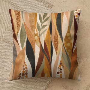 May include: A square throw pillow featuring an abstract botanical pattern of elongated leaf shapes in shades of ochre, burnt orange, sage green, cream, and charcoal. The design includes textured dot patterns and solid color blocks.
