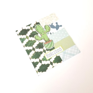 May include: A greeting card with a green cactus illustration in a striped pot. The card has a patterned background with the words "thanks a bunch" in a white rectangle. The card has a white background.