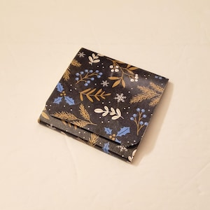 May include: A black and gold patterned gift box with a blue and white floral design. The box is folded shut and has a glossy finish.