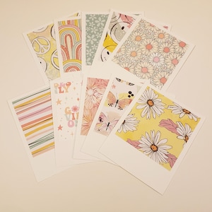 May include: Set of 10 printable digital papers featuring a variety of patterns, including daisies, butterflies, rainbows, and stars. The papers are in a pastel color palette of pink, yellow, and blue.