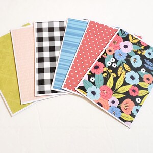 May include: A collection of decorative cards with various patterns. The patterns include a green textured design, a light pink solid color, a black and white checkered pattern, blue stripes, red polka dots, and a floral design with a black background.