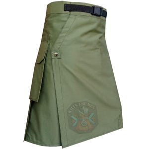 May include: Olive green utility kilt with a black belt and buckle. Features a side pocket and a decorative emblem that reads "Kilts for Men". The kilt has a wrap-around design with a button closure.