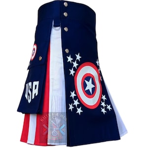 Op de afbeelding: Een marineblauwe kilt met rode en witte strepen en accenten. De kilt heeft een Captain America schildontwerp en witte sterren. Het woord "USA" is in het wit op de voorkant gedrukt. Zilveren knopen en een metalen ring zijn zichtbaar.