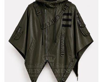 Puede incluir: Chaqueta tipo poncho con capucha verde oliva con cremallera frontal, múltiples bolsillos y correas ajustables. La chaqueta presenta detalles en negro y un dobladillo angular. Una prenda de abrigo elegante y funcional.