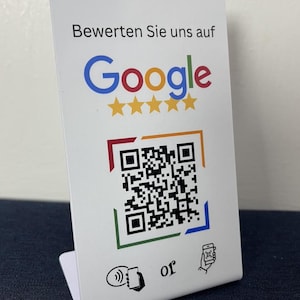 Könnte beinhalten: Weiße Karte mit dem Google-Logo und einem QR-Code. Die Karte trägt den Text "Bewerten Sie uns auf Google" und fünf goldene Sterne. Der QR-Code ist von einem roten, orangefarbenen, grünen und blauen Rahmen umgeben.