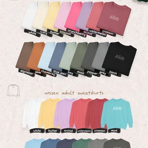May include: Color options for unisex adult t-shirts and sweatshirts in various colors, including white, ivory, butter, blossom, crunchberry, orchid, watermelon, crimson, espresso, yam, chambray, blue jean, bay, moss, pepper, grey, and black. The brand name "AIKO" is visible on some shirts.
