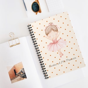 Puede incluir: Cuaderno de espiral con una cubierta crema con una ilustración de una bailarina en tutú rosa y lunares marrones. El texto "Cartas A Mi Princesa" es visible. El cuaderno está abierto sobre una superficie blanca.