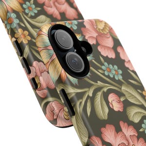 Puede incluir: Una funda para smartphone con fondo verde oliva oscuro y un patrón repetitivo de flores rosa claro, hojas verde suave y pequeñas flores azul claro. La funda tiene un recorte negro para la cámara y botones laterales negros para el volumen.