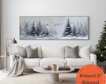 Puede incluir: Una pintura de paisaje en blanco y negro de un bosque nevado con altos árboles de hoja perenne y una bandada de pájaros. La obra de arte se exhibe sobre un sofá blanco en una sala de estar.