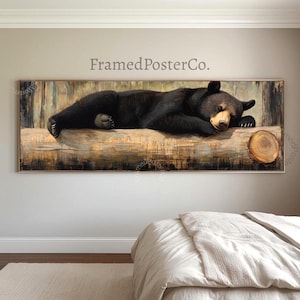 May include: A panoramic framed wall art print featuring a black bear sleeping on a large, textured wooden log. The artwork displays the text FramedPosterCo. in a neutral font above the bear. The scene is rendered in earthy tones of brown, black, and tan, capturing the bear in a resting position with its head tucked forward.