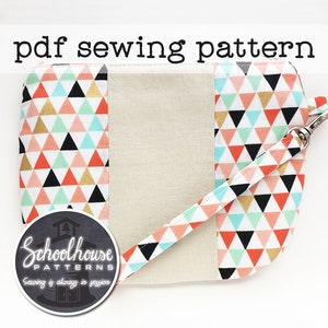 May include: A sewing pattern for a zippered pouch with a geometric print fabric and a beige fabric panel. The pouch has a strap with a metal clasp. The pattern is from Schoolhouse Patterns, with the tagline "Sewing is always in session".