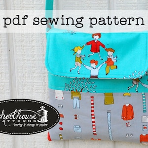 May include: PDF sewing pattern for a turquoise and gray fabric crossbody bag with a flap. The bag features a playful design of children playing and a tree with leaves. The pattern is from Schoolhouse Patterns, Sewing is always in fashion.