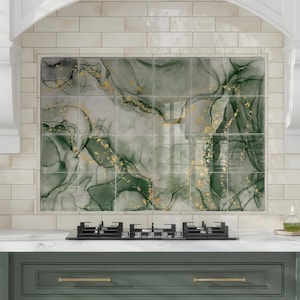 May include: Kitchen interior with green cabinets, a white countertop, and a gas hob. The backsplash features a green and gold abstract design. The kitchen has a classic design with gold hardware and white trim.