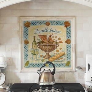 May include: A square decorative tile mural featuring a colourful illustration of a bowl of bouillabaisse, a bottle of wine, two glasses, and a baguette. The tile is centred on a light-coloured tiled backsplash above a stainless steel stovetop.