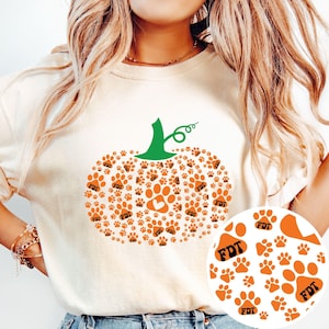 Puede incluir: Sudadera color crema con un dise&ntilde;o de calabaza hecho de huellas de patas naranjas. La calabaza tiene un tallo verde y una huella de pata en forma de coraz&oacute;n en el centro. Las letras "FDT" est&aacute;n impresas en algunas huellas.