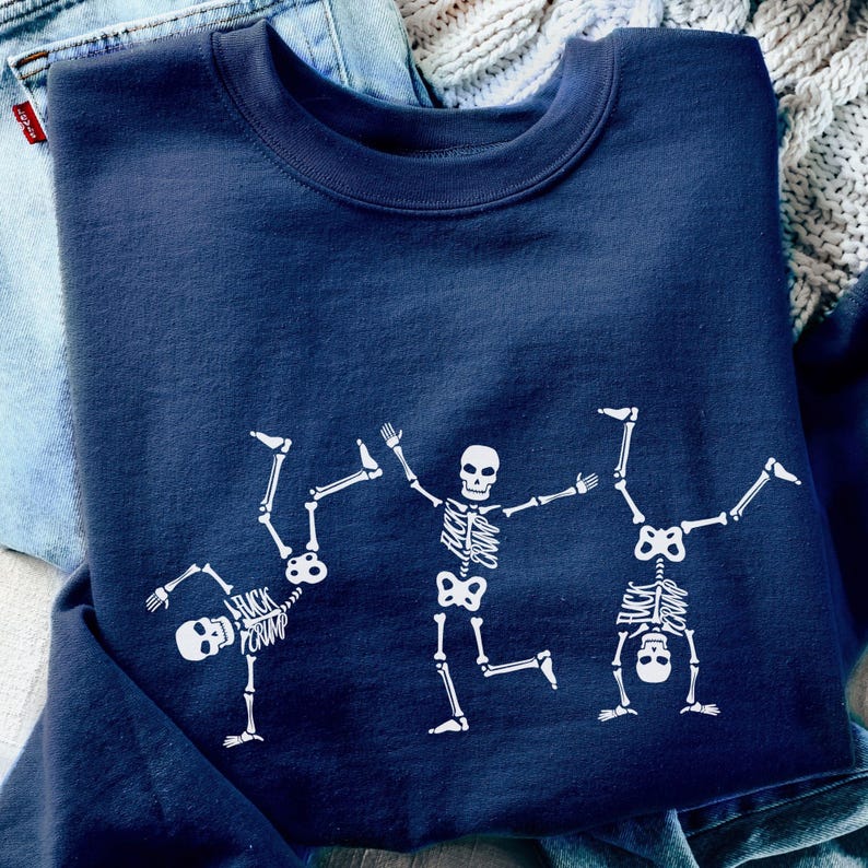 K&ouml;nnte beinhalten: Ein marineblaues Sweatshirt mit drei wei&szlig;en Skelettfiguren in spielerischen Posen. Ein Skelett macht einen Handstand, ein anderes tanzt und das dritte macht einen Handstand. Der Text "FUCK CRUMP" ist auf dem ersten Skelett aufgedruckt.