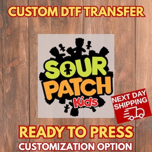 May include: A DTF transfer featuring the "Sour Patch Kids" logo in green and orange, with black silhouettes of the candy characters. The design includes the text "CUSTOM DTF TRANSFER" and "READY TO PRESS".