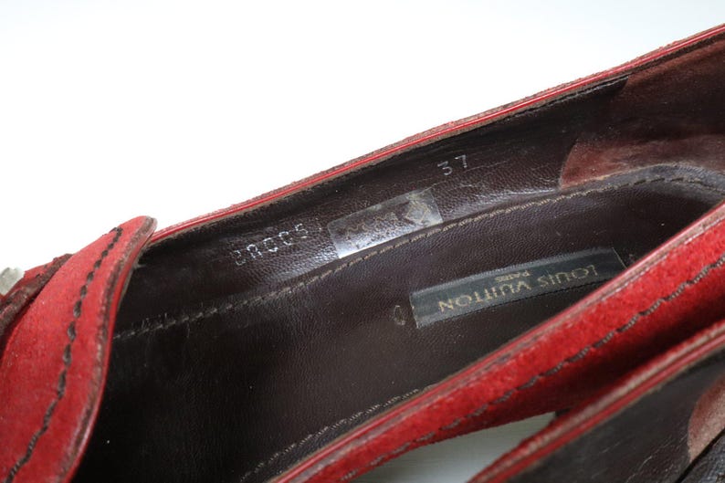 May include: Close-up of a red suede shoe interior. The shoe features a dark brown leather insole with the brand name "LOUIS VUITTON PARIS" visible. The size is marked as "37".