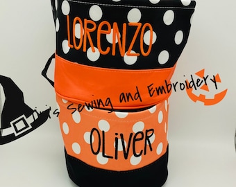 May include: Two orange and black Halloween trick-or-treat bags with white polka dots. The top bag has the name "LORENZO" embroidered on it. The bottom bag has the name "OLIVER" embroidered on it.