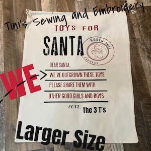 May include: White canvas Santa sack with black text that reads "Tini's Sewing and Embroidery Toys for Santa" and "Dear Santa, We've outgrown these toys. Please share them with other good girls and boys. Love. The 3 T's. Larger Size."