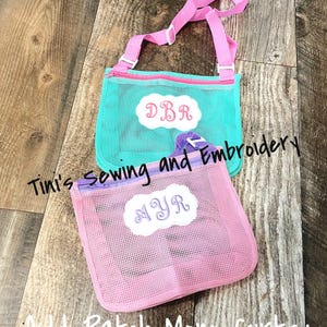 May include: Two mesh zippered bags with adjustable straps. The turquoise bag has the initials "DBR" embroidered on it. The pink bag has the initials "NYR" embroidered on it.