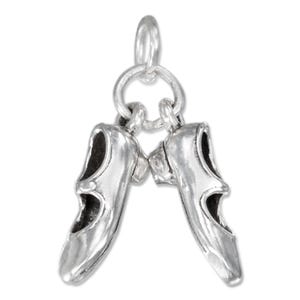 Può includere: Un ciondolo d'argento raffigurante due scarpette da ballo, collegate da un anello. Le scarpette hanno un design classico con punte arrotondate e piccoli tacchi. Il ciondolo è realizzato in metallo lucido e riflettente.