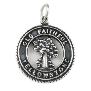 May include: A silver-toned pendant with a detailed design. The pendant features a central image of a tree-like structure, surrounded by a circular frame. The words "OLD FAITHFUL YELLOWSTONE" are inscribed around the frame.