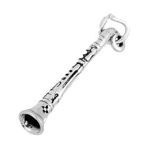 May include: A silver-colored clarinet charm with detailed engravings. The charm features a bell, a body with etched designs, and a loop for attachment. The instrument is depicted in a slightly angled view against a white background.