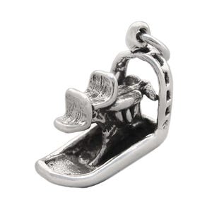 May include: A silver charm in the shape of a snowmobile. The charm is detailed with a seat, handlebars, and a track.
