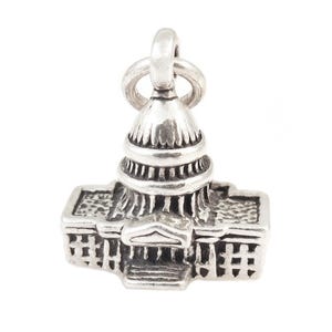 May include: Silver charm of the United States Capitol building. The charm is detailed and features a dome and columns.