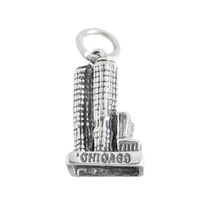 May include: Silver charm featuring a detailed miniature replica of the Chicago skyline, with the word "CHICAGO" inscribed on the base.