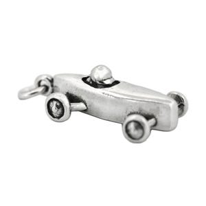 May include: Silver charm of a vintage race car with a driver. The car has a rounded body and four wheels.