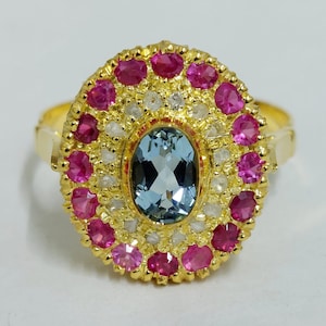 Può includere: Un anello d'oro con una grande pietra ovale di acquamarina circondata da un alone di piccole pietre rosa e bianche.