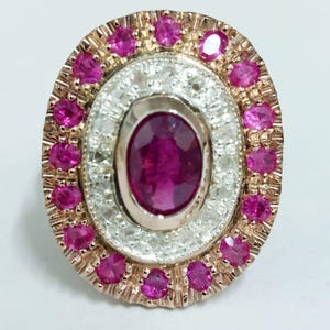 Peut inclure: Une bague avec un gros rubis ovale entouré d'un halo de petits diamants et d'une bordure de rubis roses.