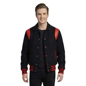 May include: A black varsity jacket with red accents on the shoulders, cuffs, and waist. The jacket has a button-up front and a classic collegiate style. The person in the image is wearing a black shirt and black pants.