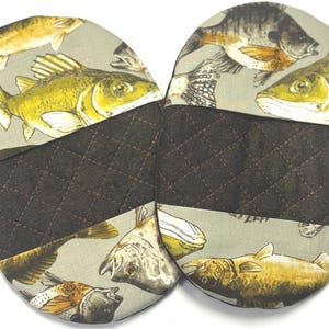 May include: Two round, quilted fabric pot holders. The top portion features a light gray background with illustrations of various fish in shades of yellow, brown, and gray. The bottom section is a dark brown quilted fabric.