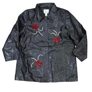 May include: Black leather jacket with red star embellishments and white accents. The jacket has a collared neckline and a button-down front. The stars are made of red sequins. The jacket is a long-sleeve style.