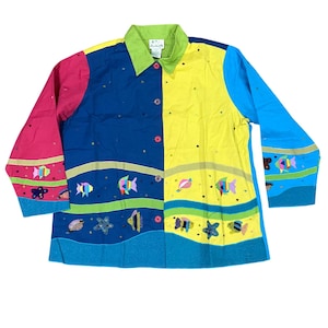 Op de afbeelding: Een kleurrijk overhemd met knopen en lange mouwen. Het overhemd is verdeeld in panelen van roze, blauw, geel en turquoise. Het heeft geborduurde vissen en zeethema-ontwerpen. De kraag is groen.