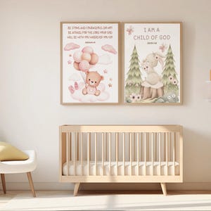 Side-by-side framed nursery prints on a pink wall: one with a bunny and John 1:12, the other with a teddy bear and Joshua 1:9. Displayed on top of the baby crib and white chair.