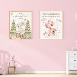 Side-by-side framed nursery prints on a pink wall: one with a bunny and John 1:12, the other with a teddy bear and Joshua 1:9. Displayed above a dresser and next to a white rocking chair and teddy bear.