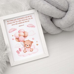 Flat-lay of a framed nursery print with a teddy bear holding balloons, featuring Joshua 1:9. Set against a white wood background with gray and white cozy textures for a soft, comforting presentation.