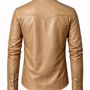 May include: A tan, long-sleeved shirt made of faux leather. The shirt has a classic collar, buttoned cuffs, and a decorative yoke on the back. The shirt is a neutral color and has a tailored fit.
