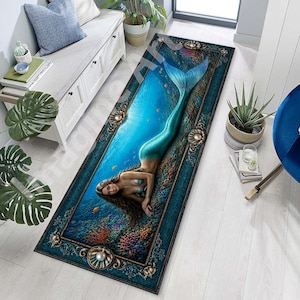 May include: A rectangular area rug featuring a mermaid design. The rug depicts a mermaid with a teal tail and long brown hair, set against an underwater scene with coral and fish. The rug has a dark teal border with pearl and shell accents.