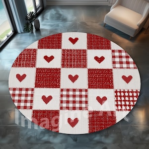Op de afbeelding: Een ronde vloerkleed met een patchwork-ontwerp. Het heeft rode harten en vierkanten in een herhalend patroon. De vierkanten wisselen af tussen rood en wit, met ruitjes en effen texturen. Een decoratieve vloerbedekking.