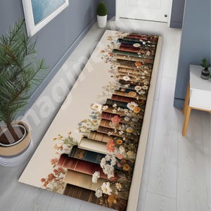 May include: A long rectangular runner rug featuring a cream-colored background with a vertical arrangement of stacked books in various shades of brown, blue, and red, interspersed with detailed illustrations of white, yellow, and orange wildflowers.