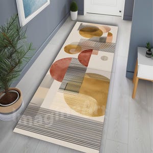 Puede incluir: Una alfombra rectangular para pasillo con un diseño abstracto. La alfombra presenta formas geométricas en tonos beige, óxido, dorado y negro. El diseño incluye círculos, líneas y formas rectangulares, creando una estética moderna.