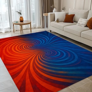 May include: A large rectangular rug with a vibrant, swirling design. The rug transitions from a warm orange hue on one side to a cool blue on the other, creating a dynamic visual effect. The pattern resembles two opposing vortexes.