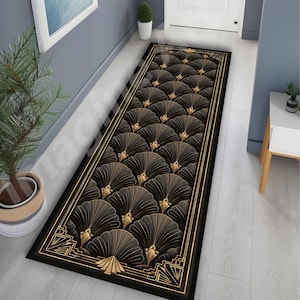 May include: A rectangular runner rug featuring a repeating pattern of dark brown fan-shaped motifs with gold-toned line accents. The rug is bordered by a thick black frame with gold geometric corner details, creating a structured and symmetrical design.