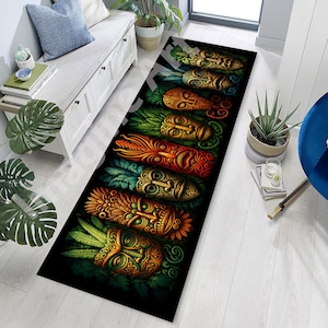 Puede incluir: Una alfombra larga y rectangular con un patrón repetido de máscaras tiki estilizadas en tonos naranja, verde y dorado sobre un fondo negro. Las máscaras tienen tallas detalladas y están rodeadas de follaje verde. La alfombra está colocada sobre un suelo de madera clara.